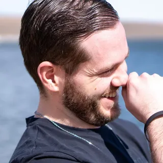 Ryan W., a PWP coaching client, laughing outdoors by the water.